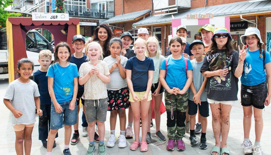 Bilden visar barnen från Barnens By sommaren 2024 tillsammans med Sandra Mobaraki (Byggsandra). Pressbild: Huddinge Samhällsfastigheter